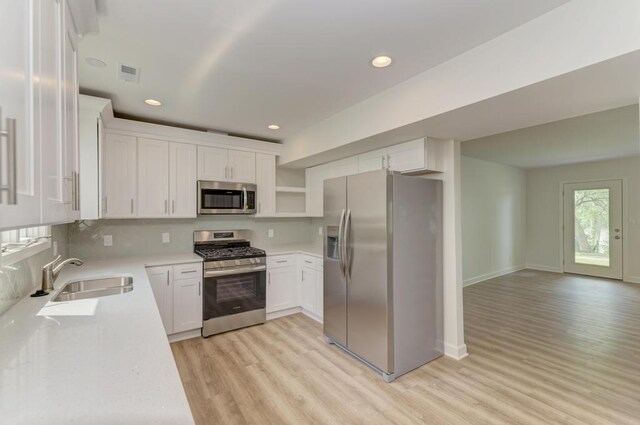1927 Lakewood Dr, Wilmington, IL 60481 - kitchen featuring appliances with stainless steel finishes, light wood finished floors, open shelves, light countertops, and white cabinets