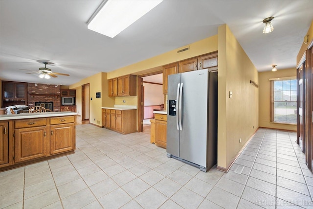 3609 Tamarisk Ct, Crystal Lake, IL 60012 - kitchen with stainless steel fridge with ice dispenser, light tile patterned floors, a brick fireplace, ceiling fan, and light countertops