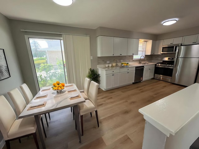15125 Waterman Dr, South Holland, IL 60473 - kitchen featuring appliances with stainless steel finishes, decorative backsplash, light countertops, white cabinetry, and light wood-style floors