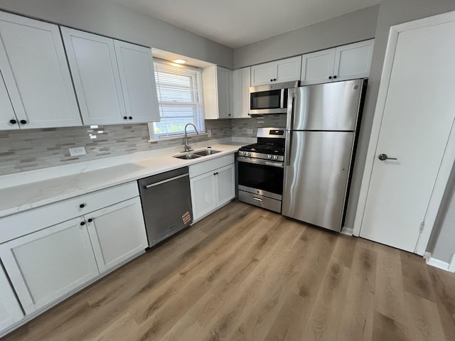 15125 Waterman Dr, South Holland, IL 60473 - kitchen with appliances with stainless steel finishes, backsplash, white cabinetry, light wood-style floors, and light stone countertops