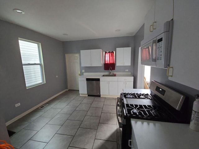 7417 S Saint Lawrence Ave, Chicago, IL 60619 - kitchen featuring appliances with stainless steel finishes, white cabinets, light countertops, light tile patterned floors, and recessed lighting