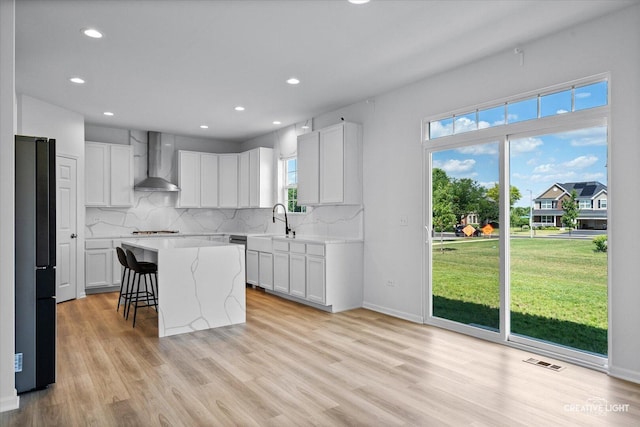 12501 S Willowgate Ln, Plainfield, IL 60585 - kitchen with wall chimney range hood, freestanding refrigerator, backsplash, light wood-style floors, and a kitchen bar