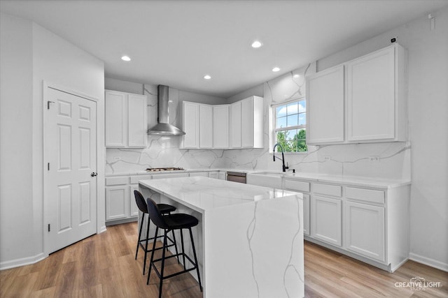 12501 S Willowgate Ln, Plainfield, IL 60585 - kitchen featuring wall chimney range hood, a kitchen island, a kitchen bar, light wood finished floors, and recessed lighting