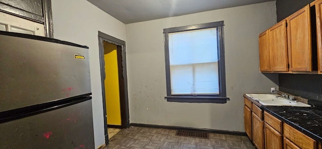 7934 S Saginaw Ave, Chicago, IL 60617 - kitchen featuring freestanding refrigerator, brown cabinetry, and dark countertops