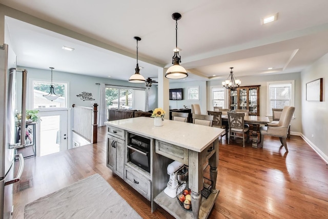 1832 N 73rd Ct, Elmwood Park, IL 60707 - kitchen featuring wood finished floors, pendant lighting, a tray ceiling, a kitchen island, and stainless steel fridge