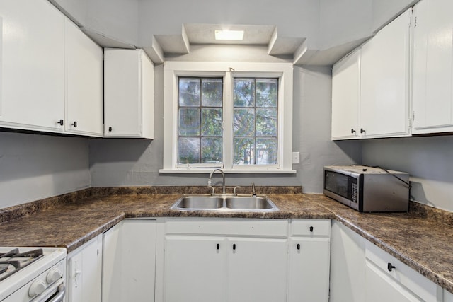 207 Smith Ave, Rockford, IL 61107 - kitchen with stainless steel microwave, white cabinets, dark countertops, and white gas range