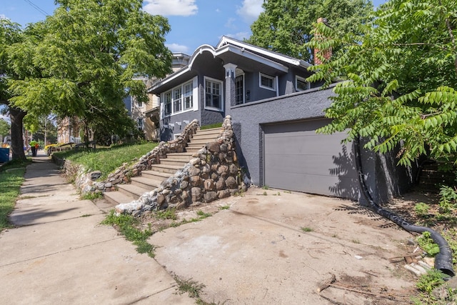 207 Smith Ave, Rockford, IL 61107 - view of front of property with concrete driveway, stairway, stucco siding, and a chimney