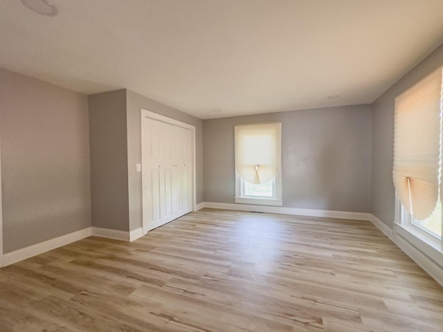 2431 Sandy Hollow Rd, Rockford, IL 61109 - unfurnished bedroom with multiple windows, light wood finished floors, and a closet