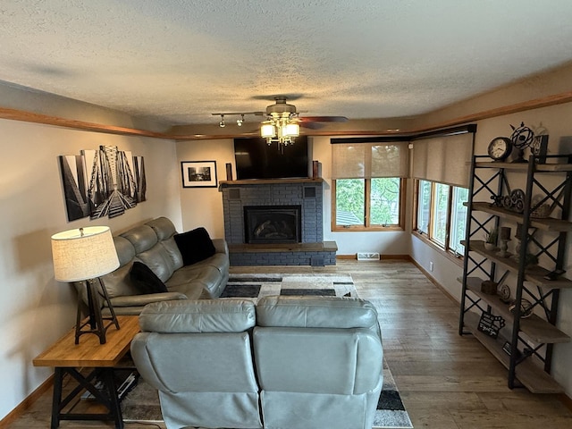 127 S Front St, Hennepin, IL 61327 - living room with ceiling fan, wood finished floors, a textured ceiling, and a brick fireplace