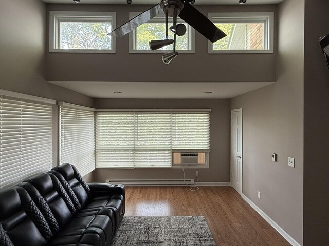127 S Front St, Hennepin, IL 61327 - living area with a high ceiling, a baseboard heating unit, wood finished floors, healthy amount of natural light, and ceiling fan