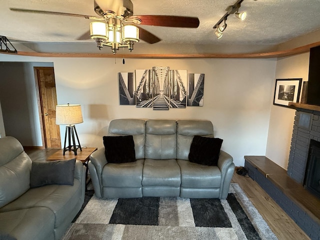 127 S Front St, Hennepin, IL 61327 - living area featuring ceiling fan, wood finished floors, a brick fireplace, and a textured ceiling