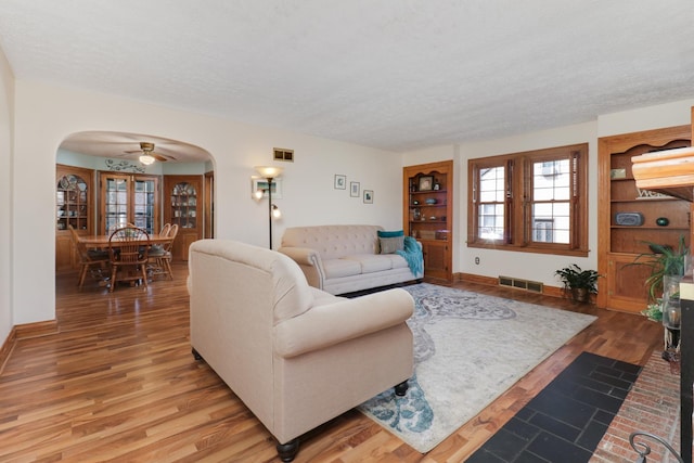 1211 Hovey Ave, Normal, IL 61761 - living room featuring arched walkways, a textured ceiling, light wood-type flooring, and a ceiling fan