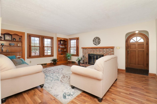 1211 Hovey Ave, Normal, IL 61761 - living area featuring arched walkways, light wood finished floors, built in features, healthy amount of natural light, and a textured ceiling
