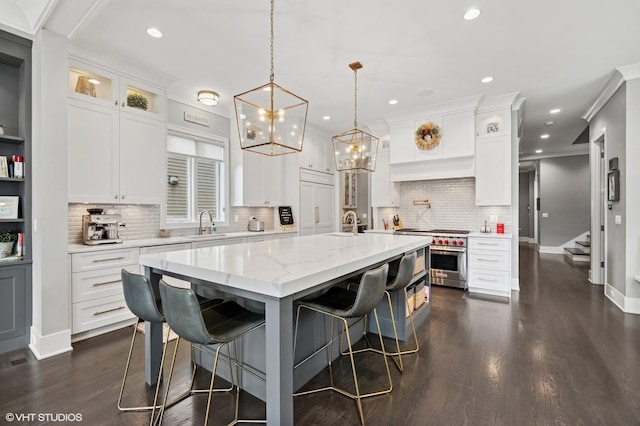 4845 N Leavitt St, Chicago, IL 60625 - kitchen featuring premium stove, backsplash, dark wood-type flooring, white cabinets, and a center island with sink