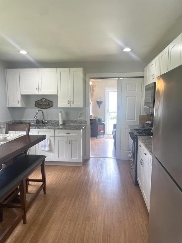 7401 W 113th Pl, Worth, IL 60482 - kitchen featuring stainless steel appliances, white cabinetry, light wood finished floors, recessed lighting, and dark stone countertops