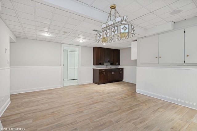 22 Westlake Dr, South Barrington, IL 60010 - kitchen with a wainscoted wall, light wood-style flooring, dark brown cabinetry, light countertops, and a drop ceiling