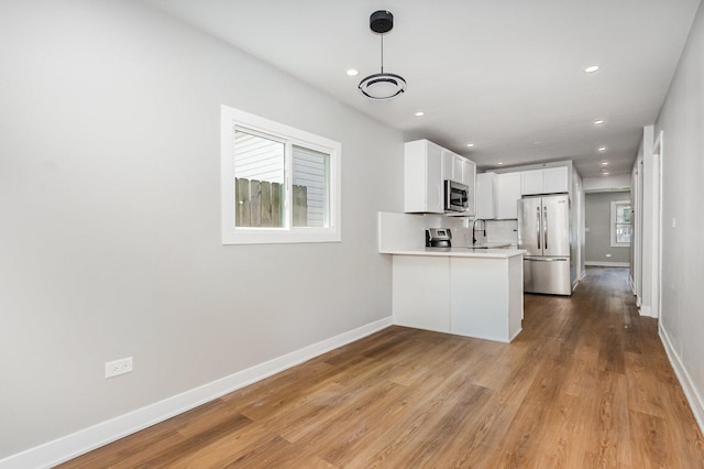 527 N Saint Louis Ave, Chicago, IL 60624 - kitchen featuring appliances with stainless steel finishes, light countertops, a peninsula, light wood-type flooring, and white cabinets