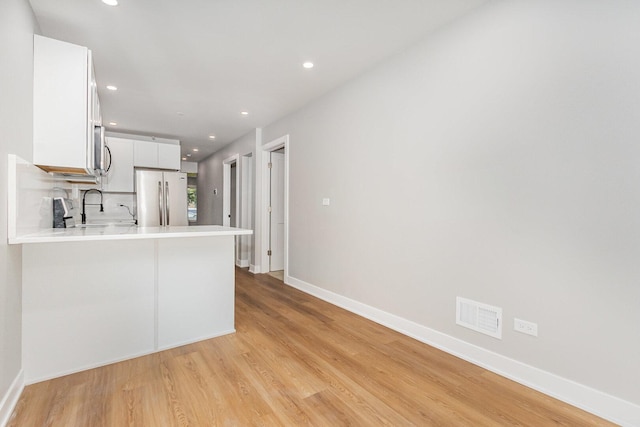 527 N Saint Louis Ave, Chicago, IL 60624 - kitchen featuring light wood-type flooring, light countertops, freestanding refrigerator, a peninsula, and white cabinets