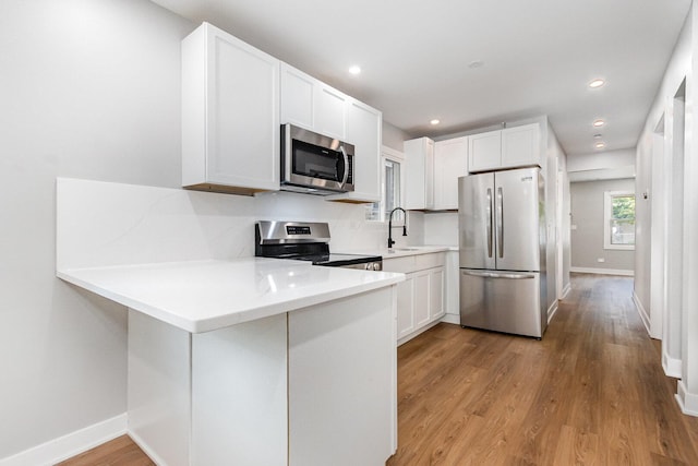 527 N Saint Louis Ave, Chicago, IL 60624 - kitchen with stainless steel appliances, a peninsula, light countertops, light wood-style flooring, and white cabinetry