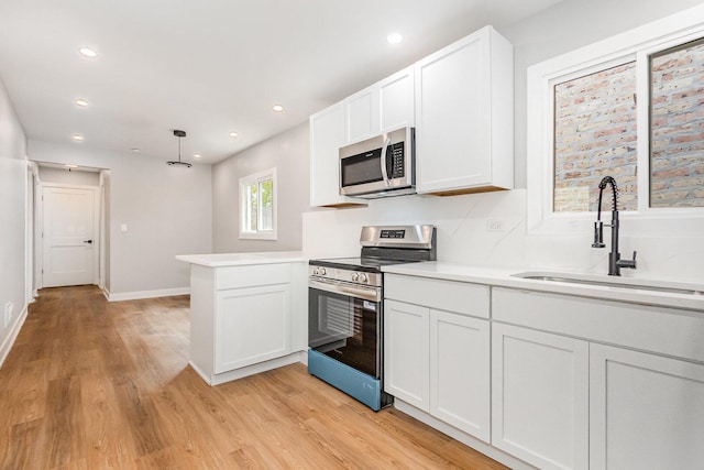 527 N Saint Louis Ave, Chicago, IL 60624 - kitchen featuring appliances with stainless steel finishes, a peninsula, light wood-style floors, white cabinets, and light countertops