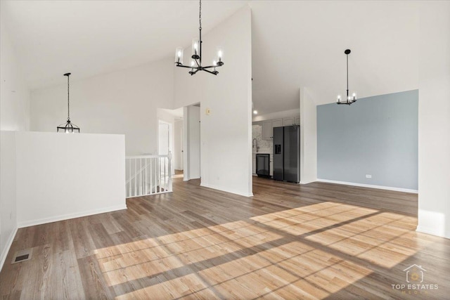 17437 Yakima Dr, Lockport, IL 60441 - unfurnished living room featuring a chandelier, high vaulted ceiling, and wood finished floors