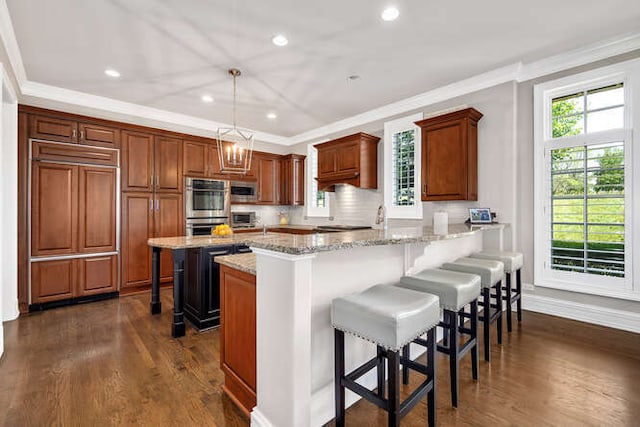 8 Willowcrest Dr, Oak Brook, IL 60523 - kitchen featuring ornamental molding, stainless steel appliances, a kitchen bar, a peninsula, and dark wood-style flooring