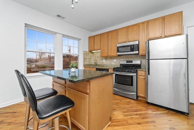 2414 W Bryn Mawr Ave Unit 1W, Chicago, IL 60659 - kitchen with appliances with stainless steel finishes, a center island, decorative backsplash, light wood-style flooring, and a kitchen bar