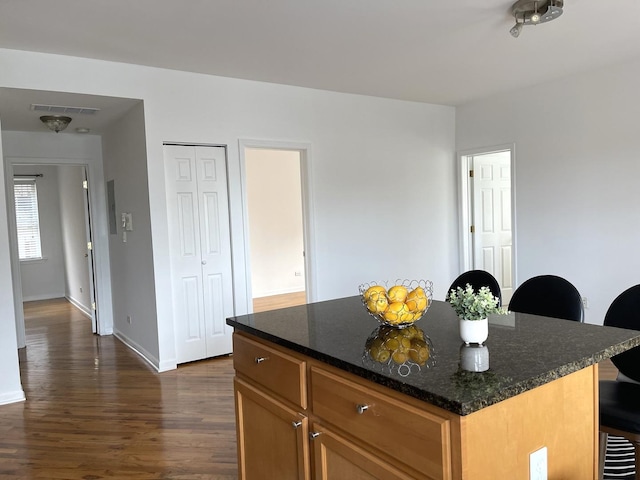 2414 W Bryn Mawr Ave Unit 1W, Chicago, IL 60659 - kitchen with dark wood-style flooring, a kitchen island, dark stone counters, and brown cabinets
