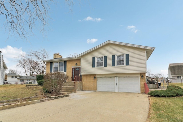 712 Dante Ct, Schaumburg, IL 60193 - split foyer home with brick siding, an attached garage, concrete driveway, and a chimney