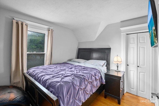 263 W Illinois Ave, Aurora, IL 60506 - bedroom with light wood-style floors, vaulted ceiling, a textured ceiling, and a closet