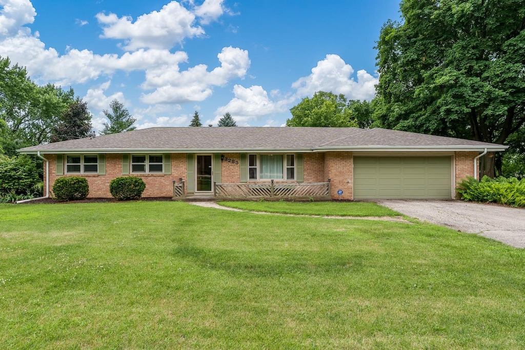 3285 Samuelson Rd, Rockford, IL 61109 - single story home with an attached garage, asphalt driveway, brick siding, and a front yard