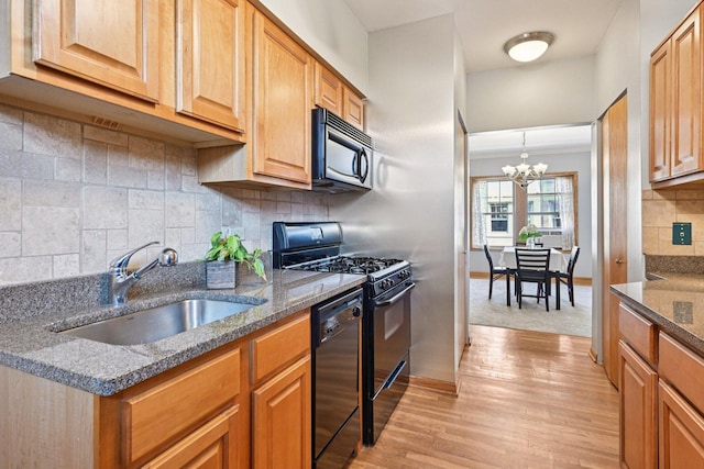245 W Washington Blvd Unit 2B, Oak Park, IL 60302 - kitchen featuring black appliances, a chandelier, tasteful backsplash, light wood-style flooring, and dark stone countertops