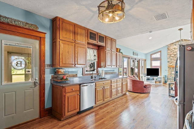 887 N 1100e Rd, Melvin, IL 60952 - kitchen featuring appliances with stainless steel finishes, vaulted ceiling, a textured ceiling, light wood-style flooring, and brown cabinetry