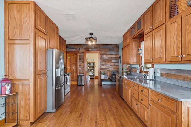 887 N 1100e Rd, Melvin, IL 60952 - kitchen with stainless steel appliances, light wood-style flooring, brown cabinetry, a textured ceiling, and wood walls