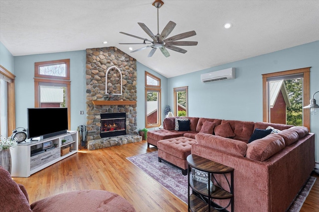 887 N 1100e Rd, Melvin, IL 60952 - living area with a wall mounted air conditioner, lofted ceiling, ceiling fan, a stone fireplace, and wood finished floors
