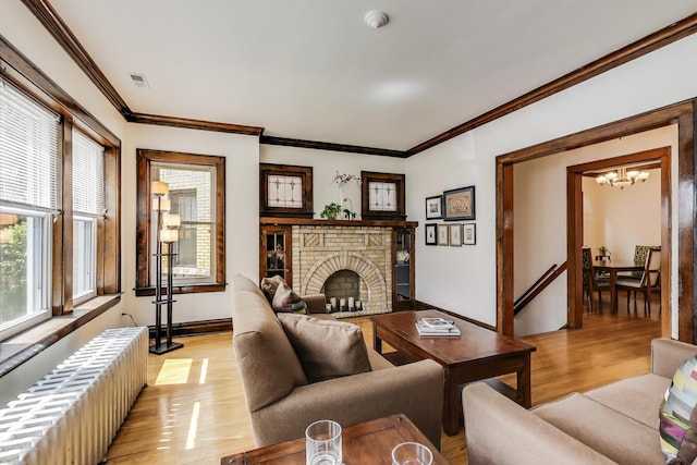 3740 N Whipple St, Chicago, IL 60618 - living room with radiator, a chandelier, light wood-type flooring, a fireplace, and ornamental molding