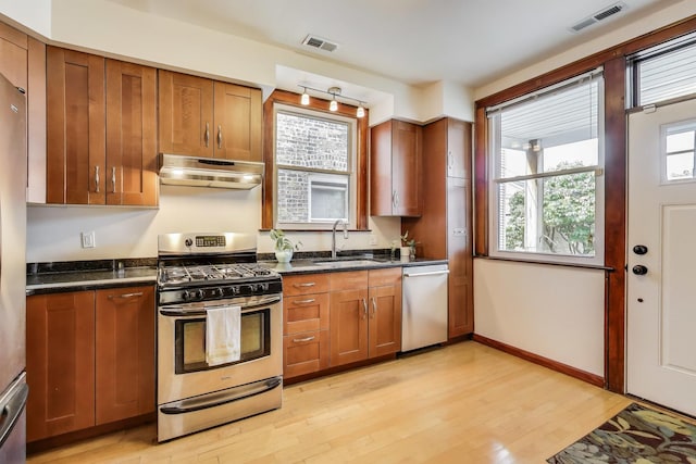 3740 N Whipple St, Chicago, IL 60618 - kitchen with stainless steel appliances, under cabinet range hood, light wood-type flooring, and brown cabinetry