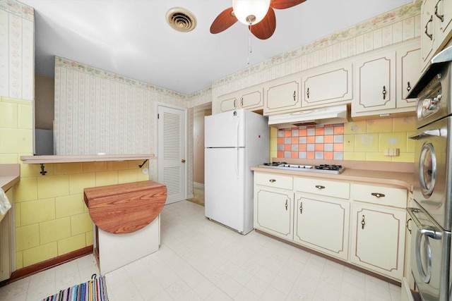 5504 Oakdale Dr, Oak Lawn, IL 60453 - kitchen with freestanding refrigerator, wallpapered walls, gas cooktop, a ceiling fan, and under cabinet range hood