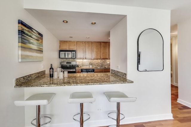 30 E Huron St Unit 2602, Chicago, IL 60611 - kitchen with appliances with stainless steel finishes, light wood finished floors, tasteful backsplash, a kitchen bar, and stone countertops