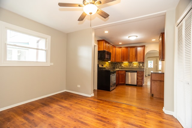 1103 Circle Ave, Forest Park, IL 60130 - kitchen featuring stainless steel appliances, arched walkways, decorative backsplash, wood finished floors, and dark countertops