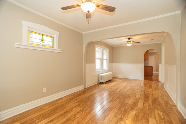 1103 Circle Ave, Forest Park, IL 60130 - empty room featuring radiator heating unit, arched walkways, ceiling fan, light wood-style flooring, and a wainscoted wall