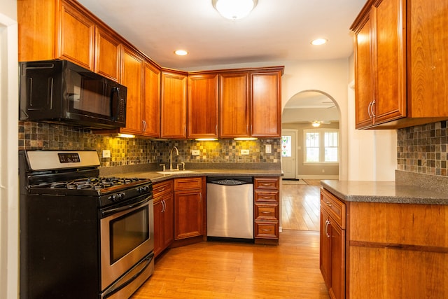 1103 Circle Ave, Forest Park, IL 60130 - kitchen featuring appliances with stainless steel finishes, light wood-type flooring, arched walkways, dark countertops, and tasteful backsplash