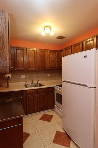 815 Grove Dr Unit 112, Buffalo Grove, IL 60089 - kitchen featuring freestanding refrigerator, stainless steel range oven, light tile patterned floors, light countertops, and brown cabinetry