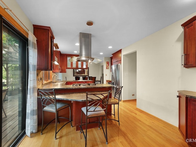 780 Chisholm Trl, Roselle, IL 60172 - kitchen with dark brown cabinets, appliances with stainless steel finishes, island exhaust hood, light wood finished floors, and a peninsula