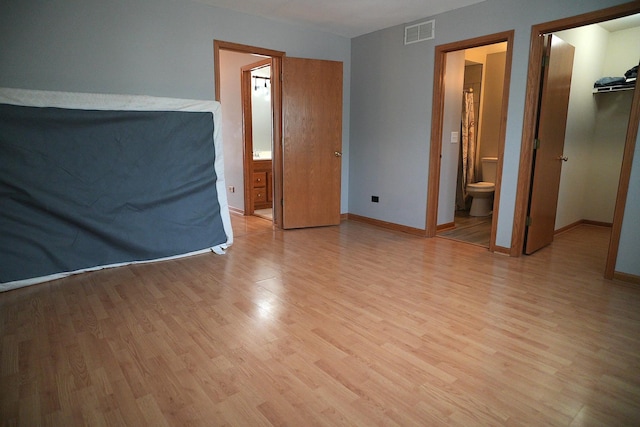 182 Cherrywood Ct, Romeoville, IL 60446 - unfurnished bedroom featuring a walk in closet, light wood finished floors, ensuite bath, and a closet