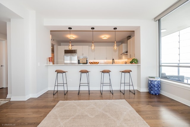600 N Lake Shore Dr Unit 1905, Chicago, IL 60611 - kitchen with stainless steel appliances, a breakfast bar area, wood finished floors, and wall chimney exhaust hood