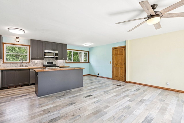 1020 Cassie Dr, Joliet, IL 60435 - kitchen with appliances with stainless steel finishes, a kitchen island, backsplash, light countertops, and gray cabinets
