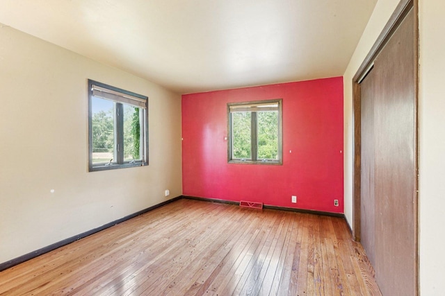1020 Cassie Dr, Joliet, IL 60435 - unfurnished bedroom featuring multiple windows, hardwood / wood-style flooring, and a closet