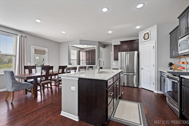 2267 Lundquist Dr, Aurora, IL 60503 - kitchen featuring appliances with stainless steel finishes, a kitchen island with sink, dark wood-type flooring, recessed lighting, and light stone countertops