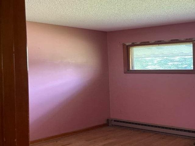 118 National Ave, Danville, IL 61832 - unfurnished room featuring a baseboard radiator, light wood-style floors, and a textured ceiling
